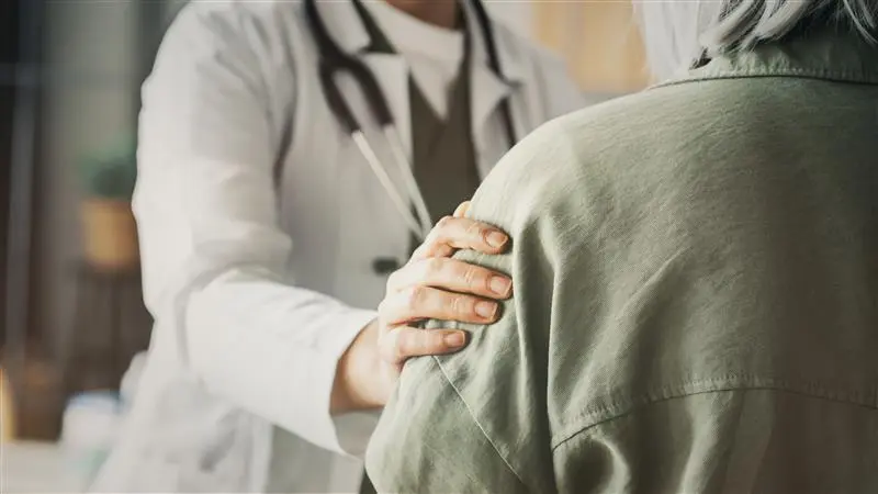 Ärztin legt einer Patientin fürsorglich die Hand auf die Schulter
